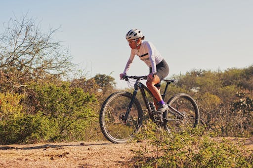 A woman mountain biking on a sunny day in the Mexican outdoors, surrounded by nature.